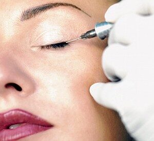 Woman receiving eyeliner tattoo.
